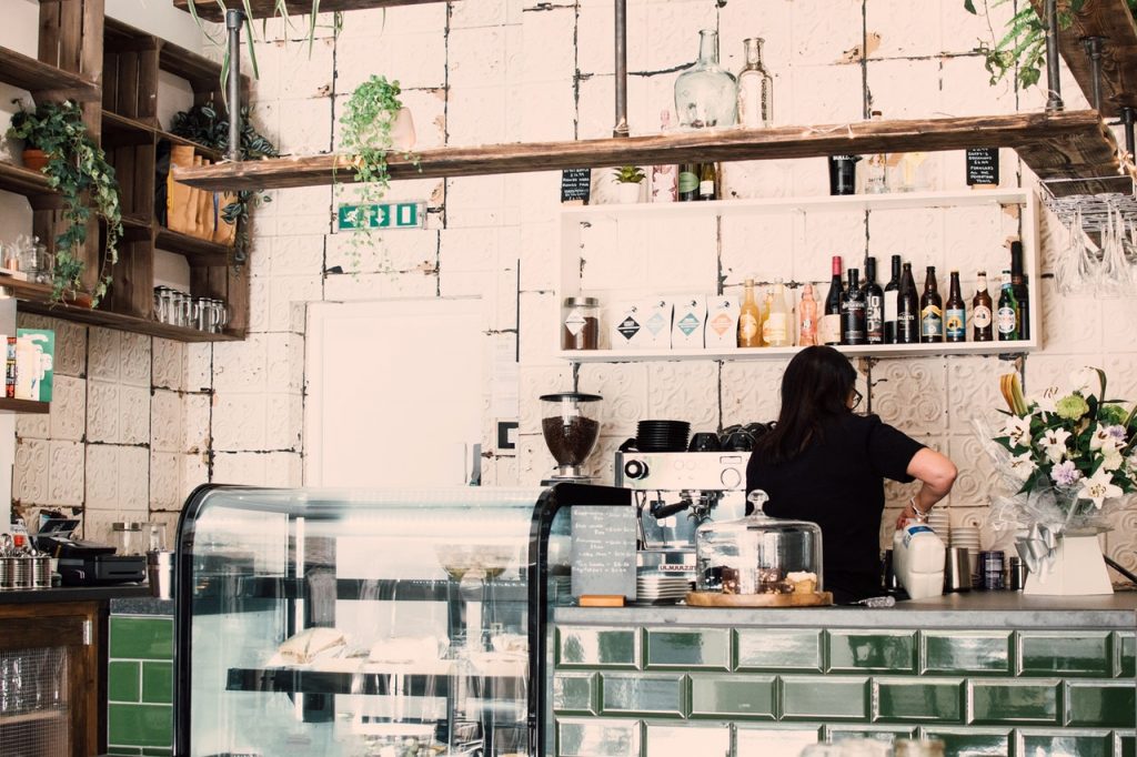 cafe bar with timber shelving on white walls and emerald tiles on counter